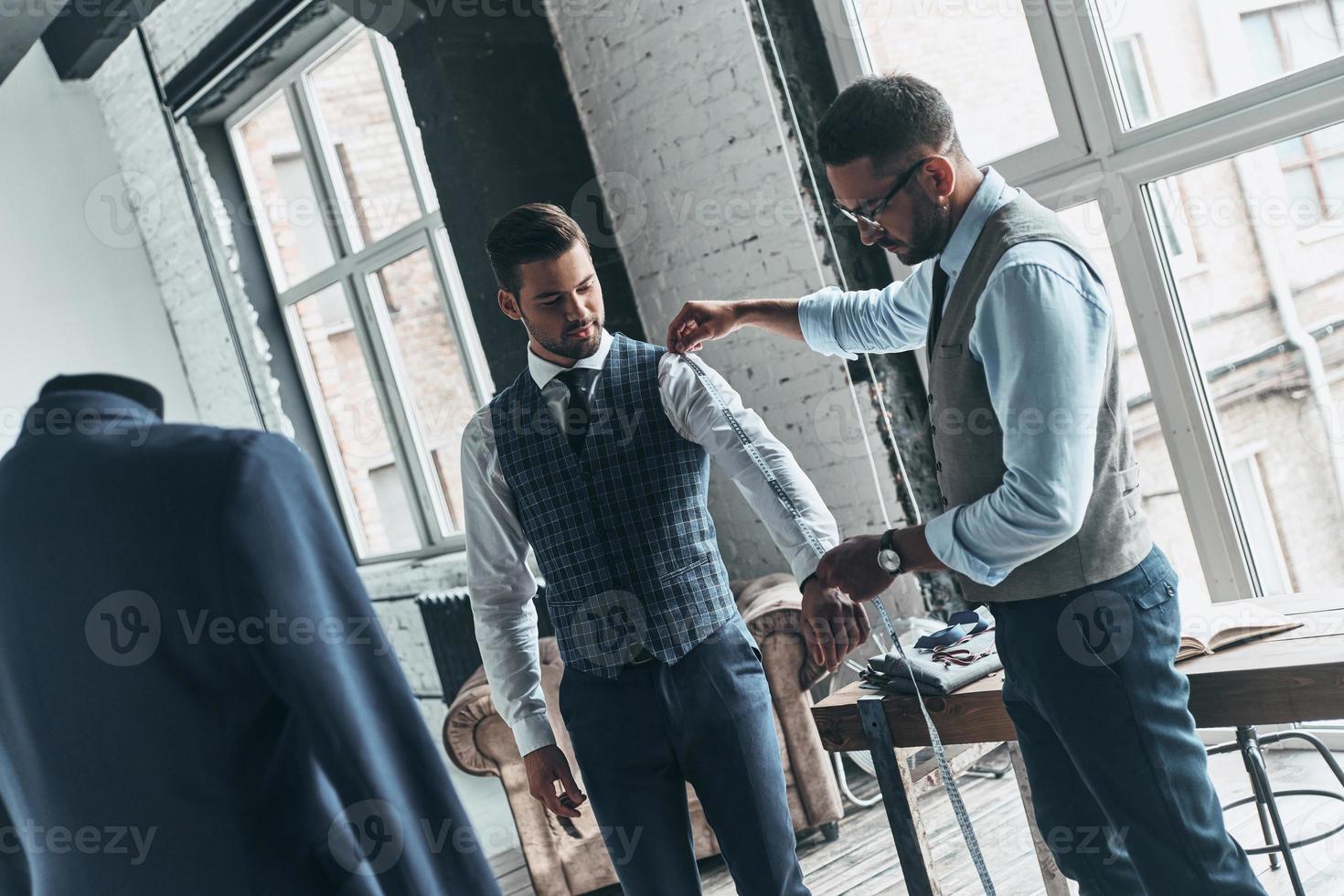 zwei junge modische Männer, die Jacken messen foto