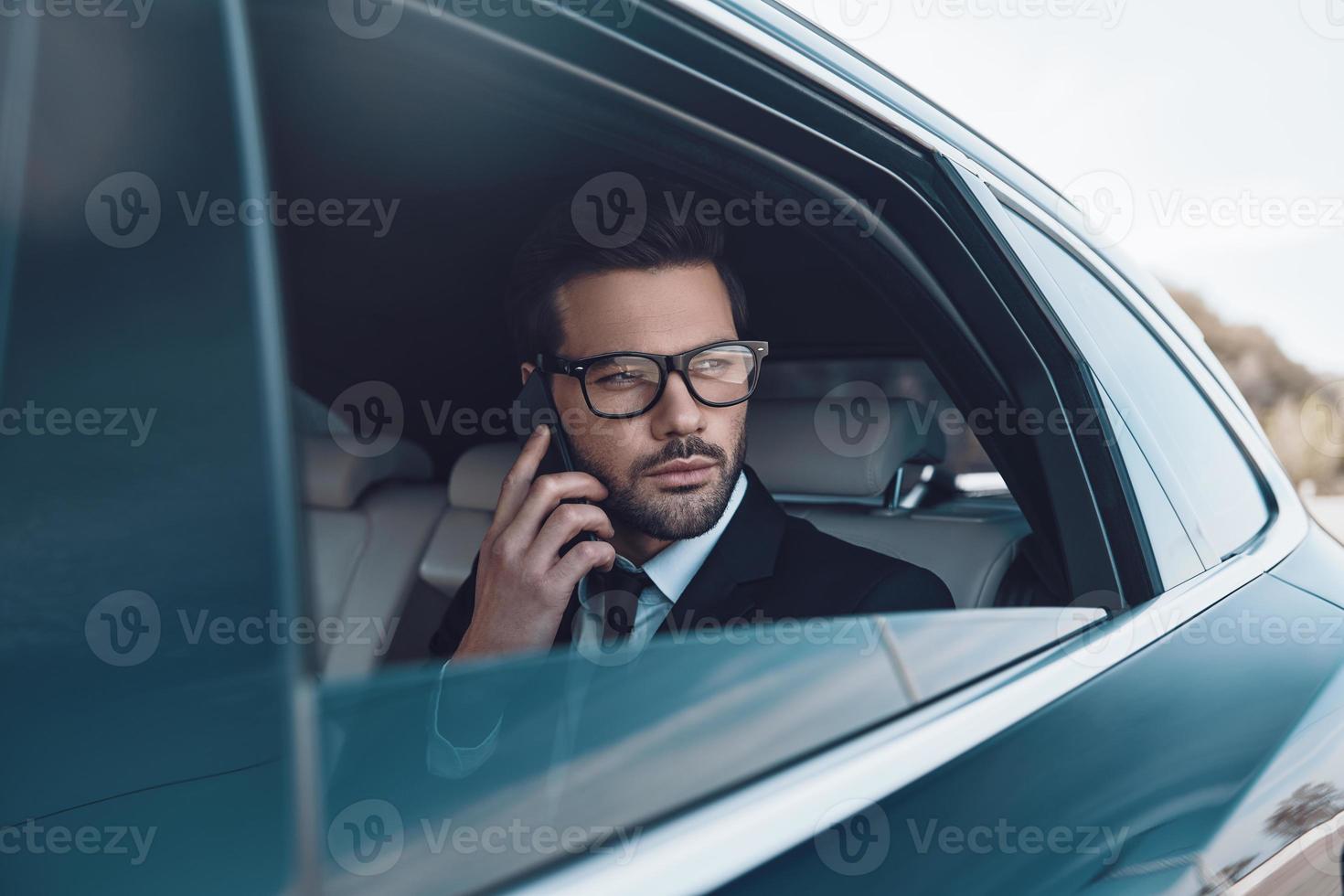 Geschäftsdetails besprechen. nachdenklicher junger geschäftsmann, der am telefon spricht, während er im auto sitzt foto