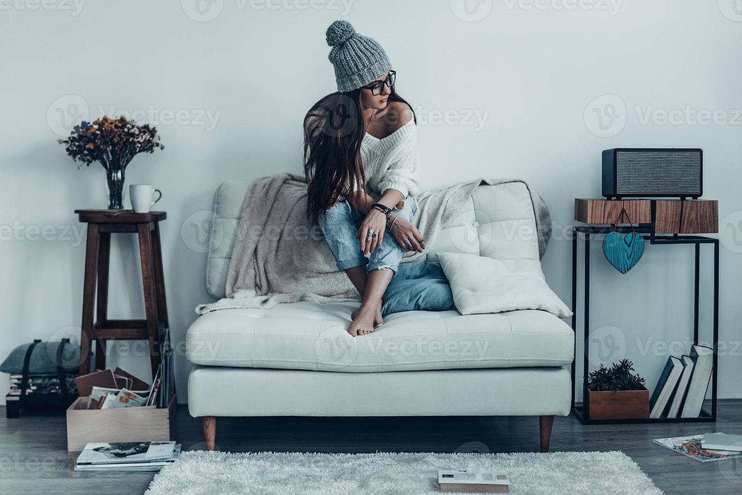 gibt sich Zeit zum Träumen. nachdenkliche junge Frau in Freizeitkleidung, die wegschaut, während sie zu Hause auf dem Sofa sitzt foto