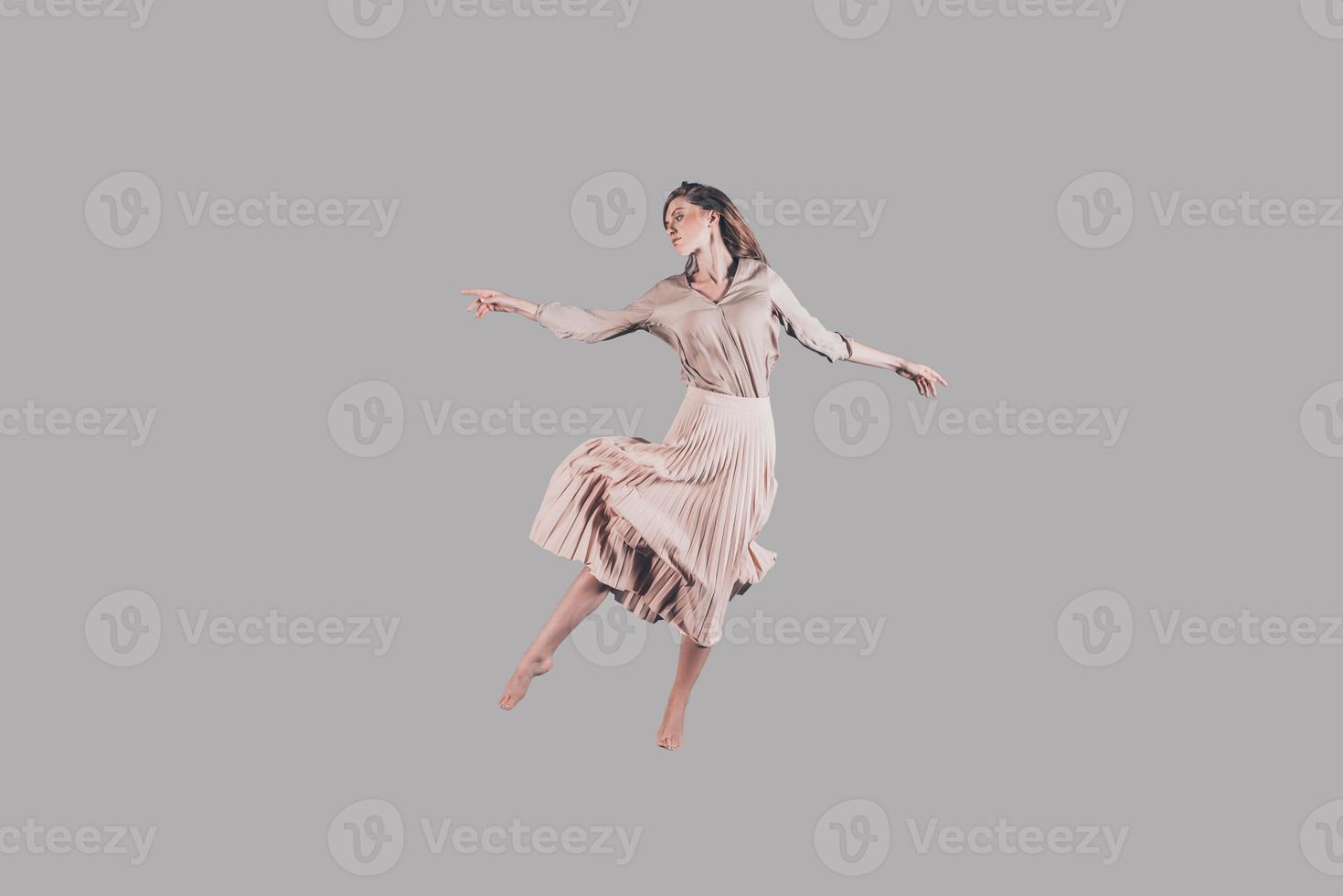 Tanzkönigin. Studioaufnahme einer attraktiven jungen Frau in schönem Kleid, die in der Luft schwebt foto