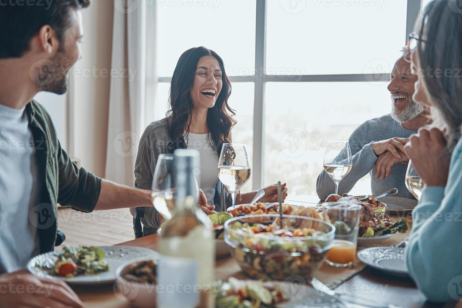 glückliche Mehrgenerationenfamilie, die beim gemeinsamen Abendessen kommuniziert und lächelt foto