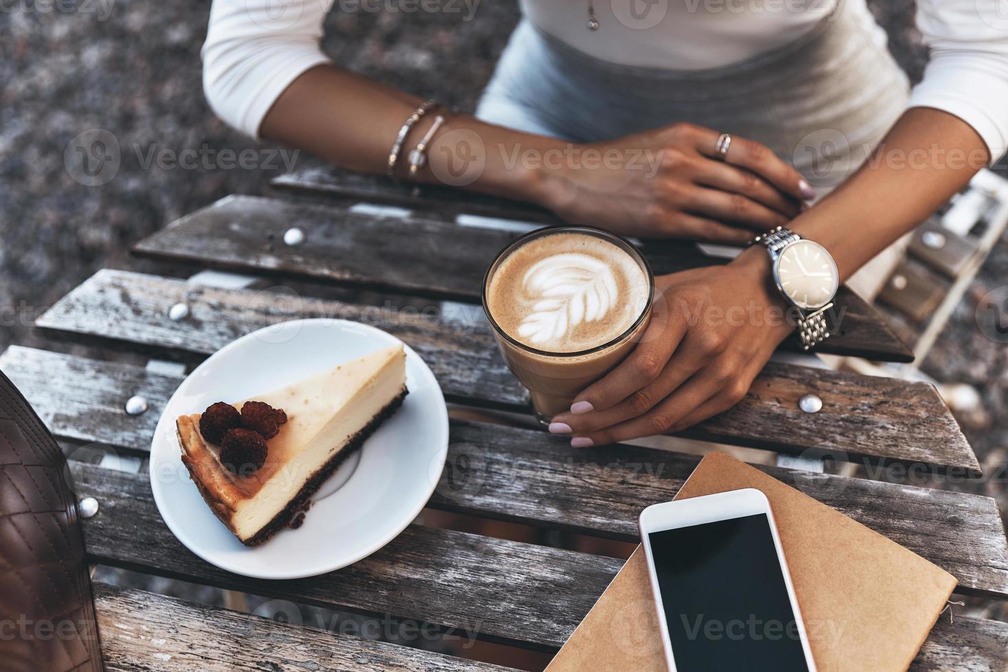 schmackhaftes Mittagessen genießen. Nahaufnahme von oben einer jungen Frau, die eine Tasse Kaffee hält, während sie im Restaurant im Freien sitzt foto