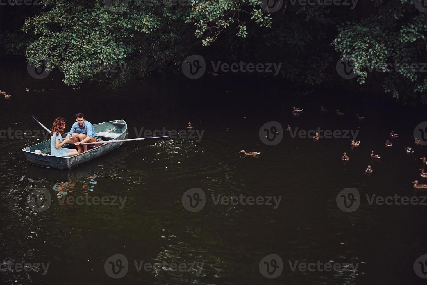 Schönheit der Natur. Draufsicht auf schöne junge Paare, die Enten füttern, während sie ein Boot rudern foto