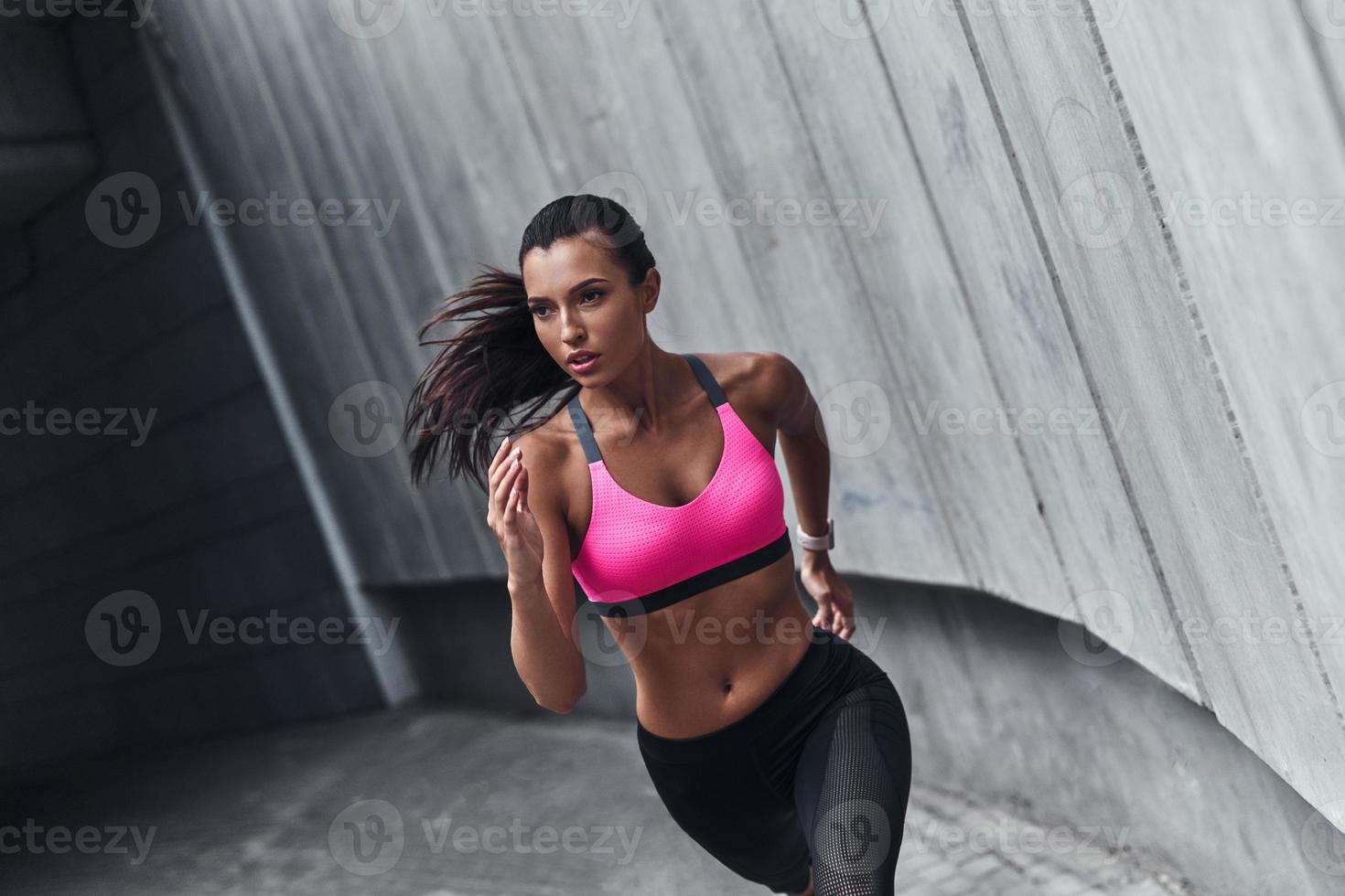 bestes Cardio aller Zeiten. Moderne junge Frau in Sportkleidung läuft beim Training im Freien foto