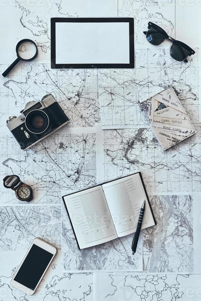 einfach reisen. Hochwinkelaufnahme von Sonnenbrille, Fotokamera, Kompass, Lupe, Tagebuch, Smartphone und Reisepass auf der Karte foto