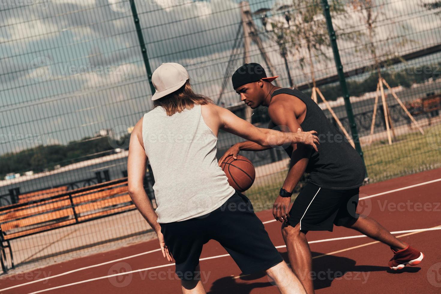 Wettbewerb. Zwei junge Männer in Sportkleidung spielen Basketball und verbringen Zeit im Freien foto