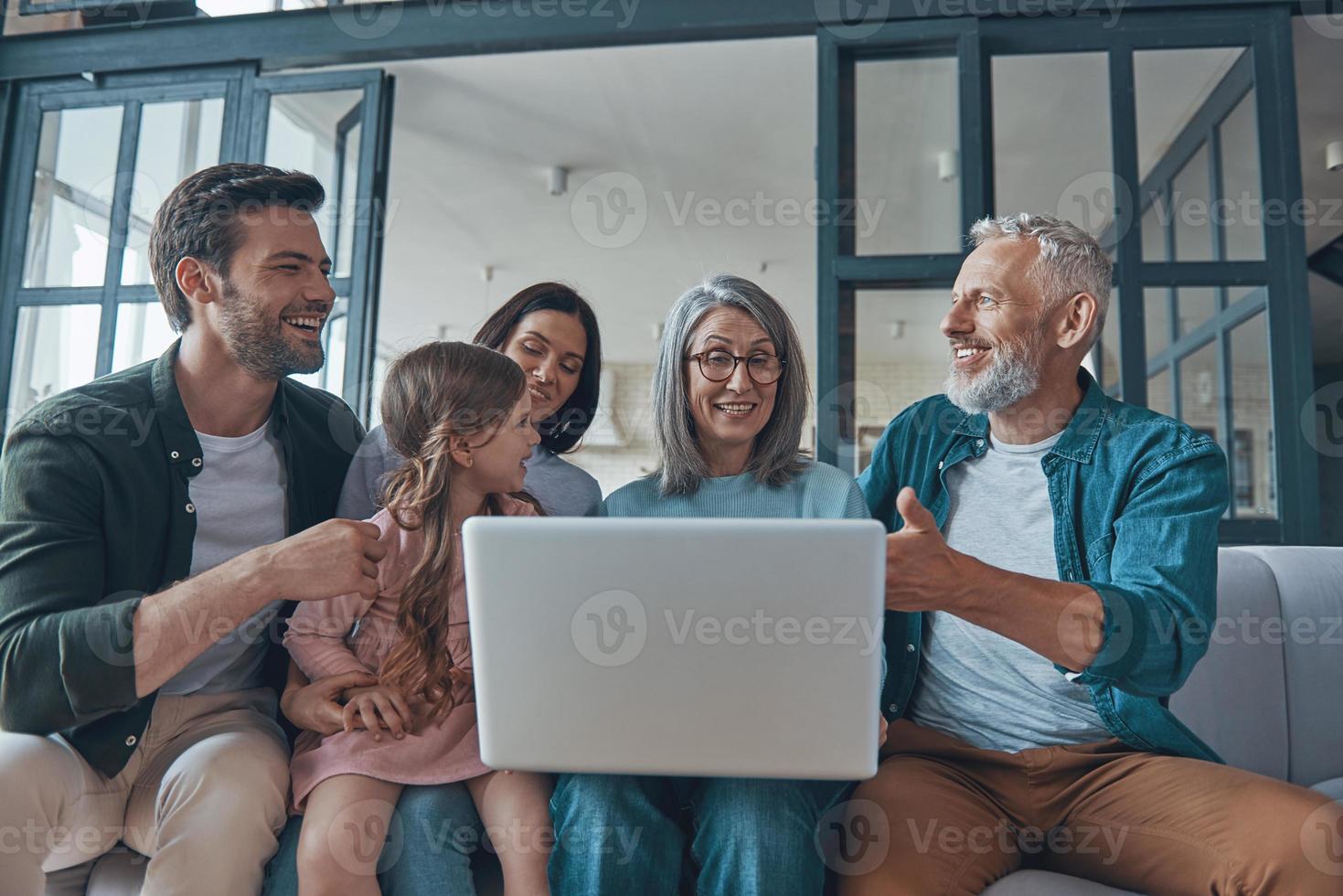 glückliche familie, die laptop verwendet und lächelt, während sie zeit zu hause zusammen verbringt foto