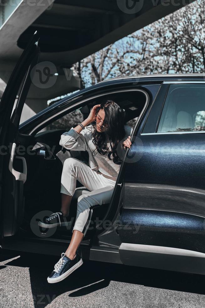 Schönheit im Stil. attraktive junge, stilvolle frau mit brille, die aus ihrem auto steigt foto