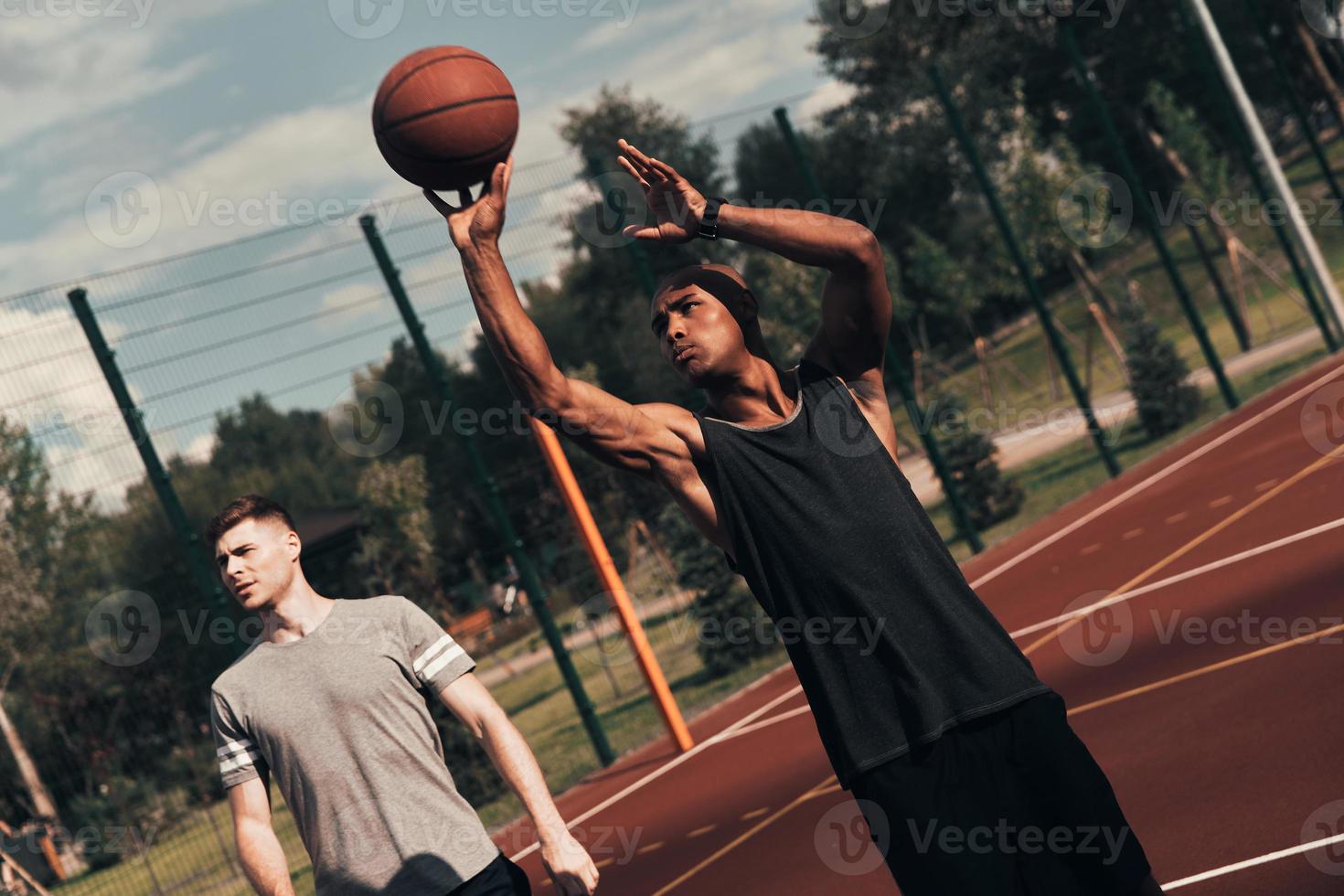 bereit zum Schießen. Zwei junge Männer in Sportkleidung spielen Basketball und verbringen Zeit im Freien foto