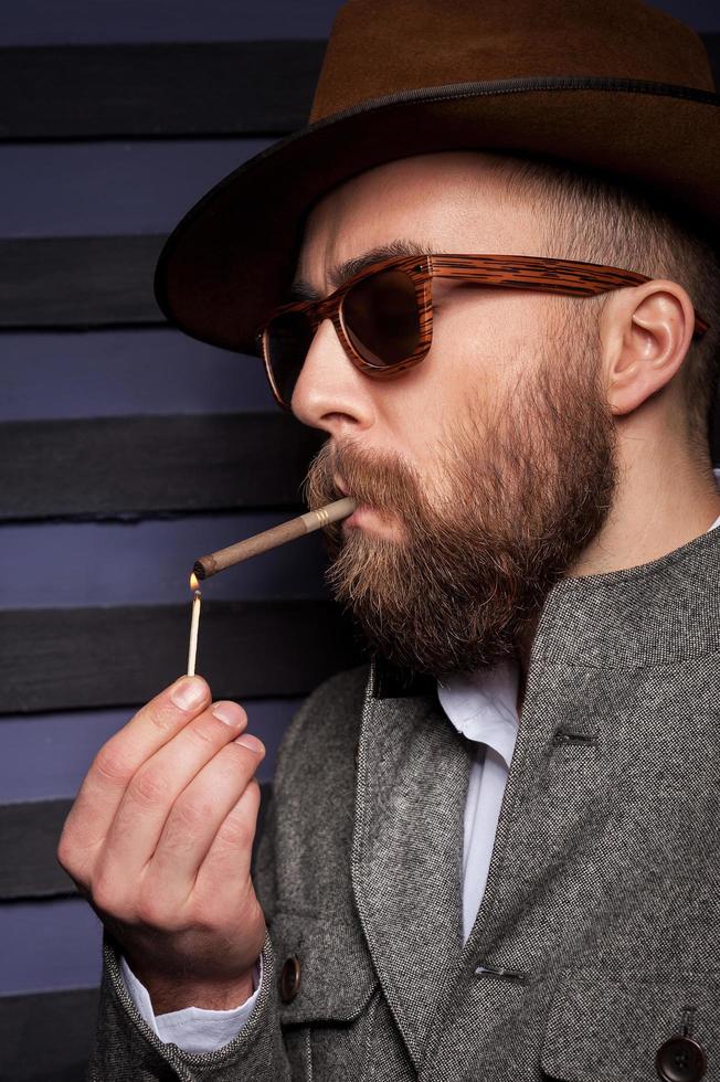 eine Pause zum Rauchen einlegen. hübscher junger Mann mit Sonnenbrille zündet sich eine Zigarette an foto