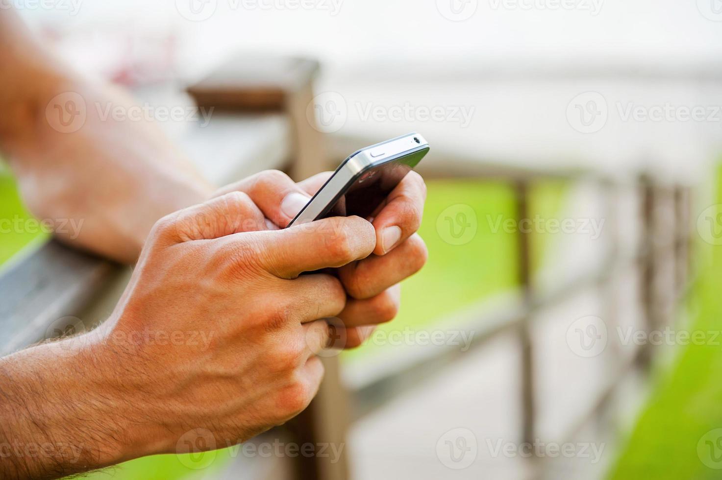 Nachricht an einen Freund. Nahaufnahme eines Mannes, der eine Nachricht auf dem Handy eingibt, während er im Freien steht foto