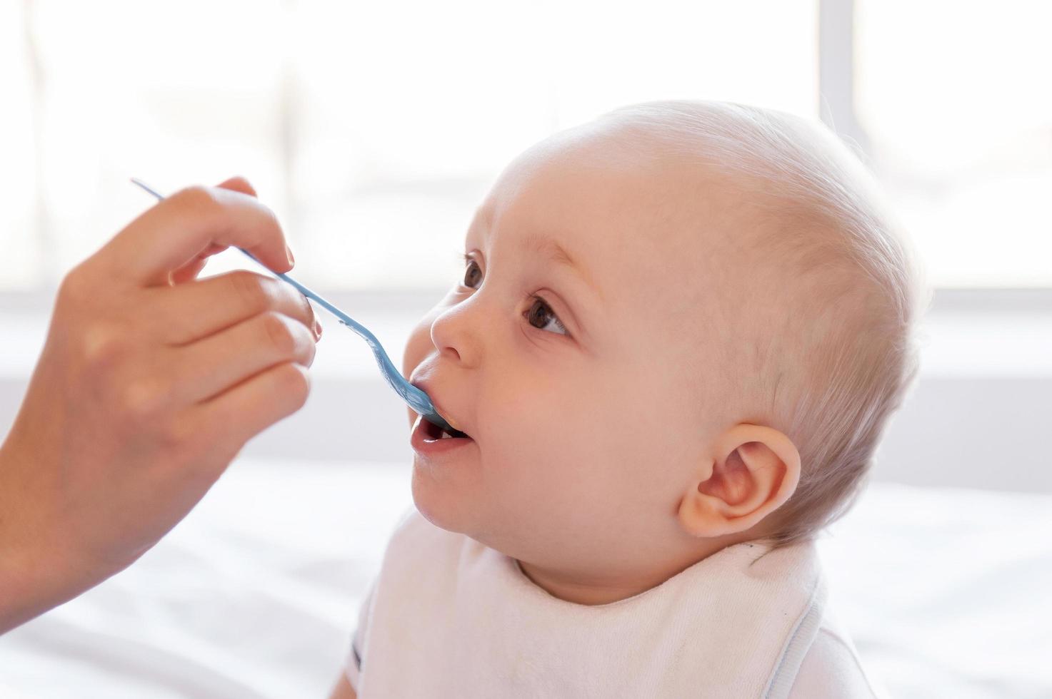 Mutter weiß, was ich mag. Nahaufnahme der Mutterhand, die ihr kleines Baby füttert foto