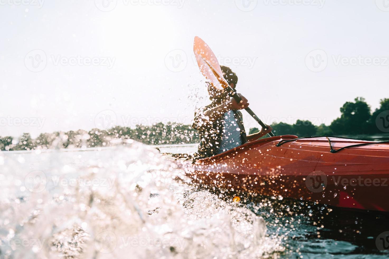 Flussabenteuer. Junger Mann Spritzwasser beim Kajakfahren auf dem Fluss foto