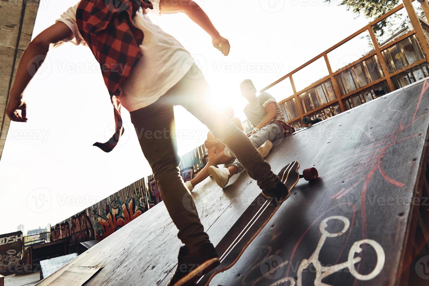 extreme Freiheit. moderner junger Mann, der Skateboard fährt, während er mit seinen Freunden im Freien rumhängt foto