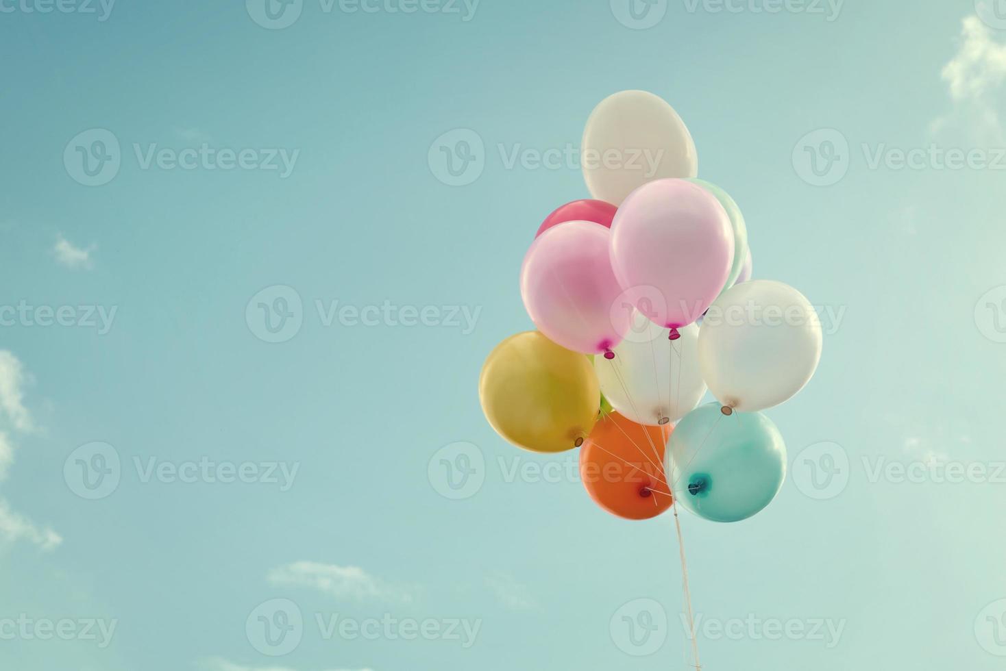 Bündel Luftballons, die im strahlend blauen Himmel schweben foto