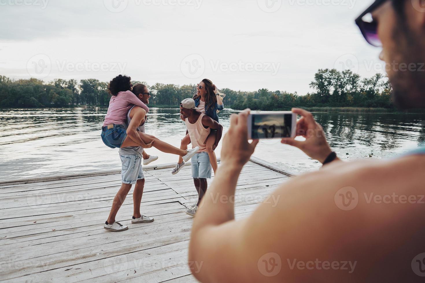 Schöne junge Paare, die unbeschwerte Zeit verbringen, während sie auf dem Pier stehen foto