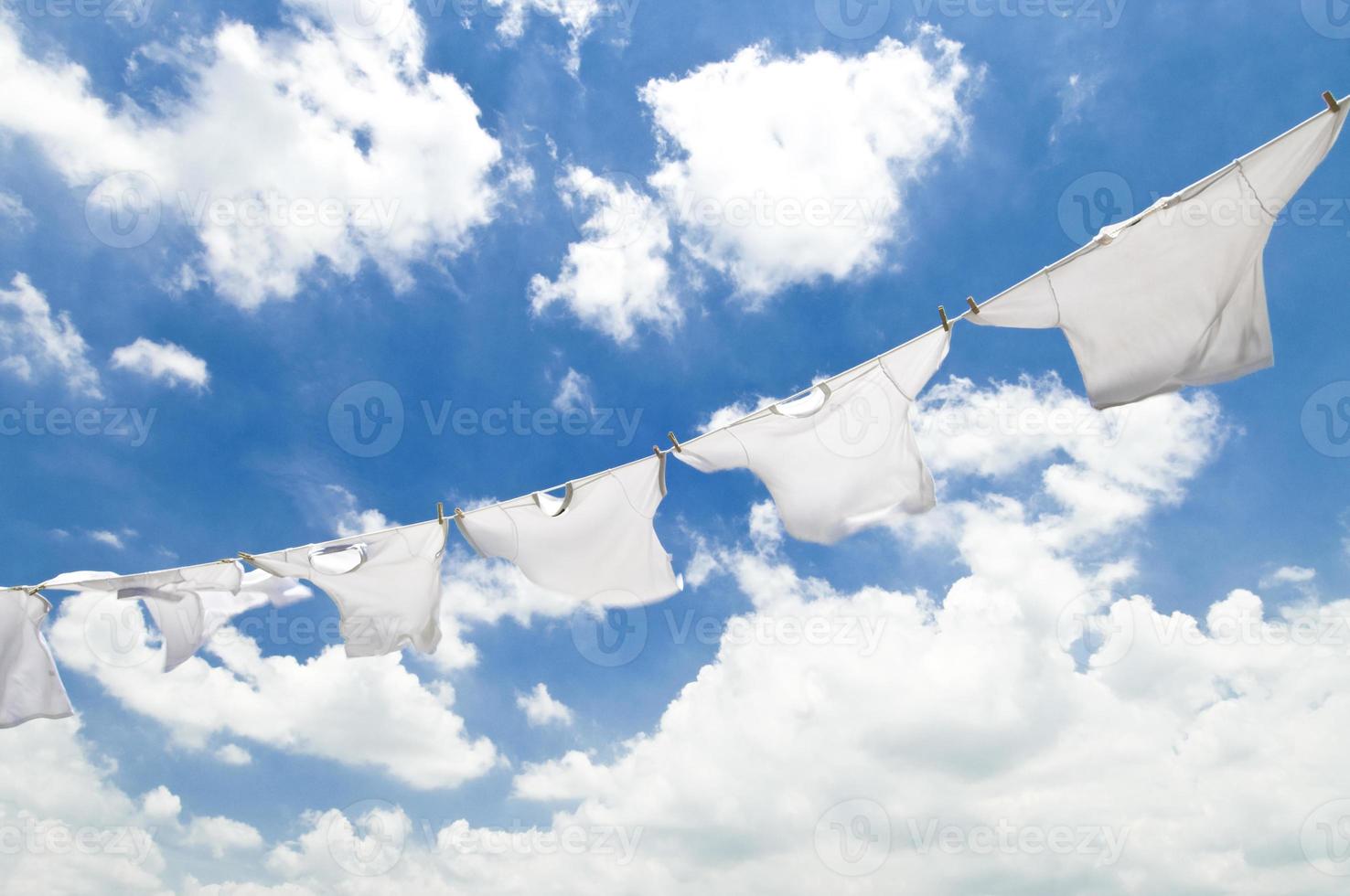 weiße Kleidung auf einer Wäscheleine gegen einen bewölkten Himmel foto