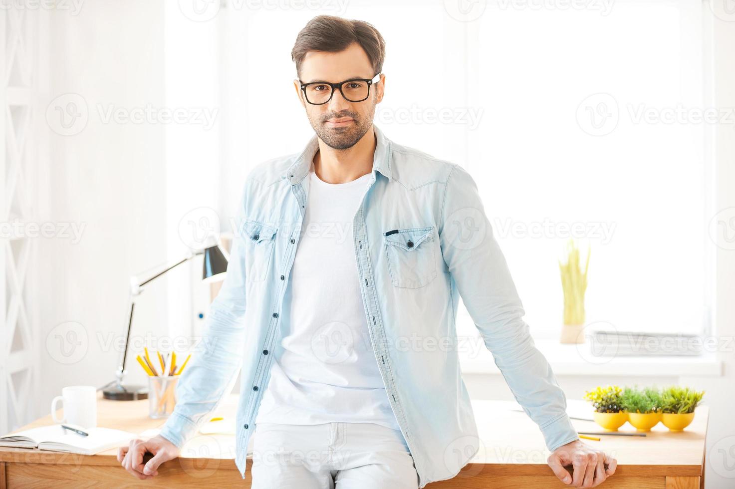 ich liebe meinen job hübscher junger mann, der in der nähe seines arbeitsplatzes steht und in die kamera schaut foto