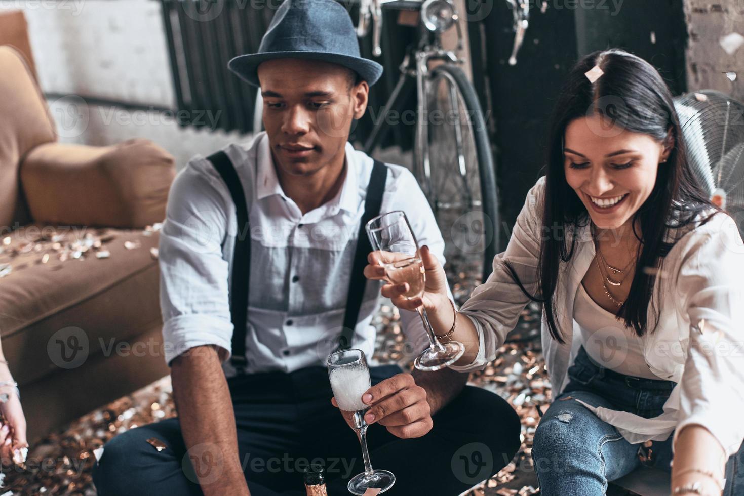 einfach nur Entspannen. Draufsicht des modernen jungen Mannes, der Champagner trinkt, während er mit seinem Freund auf dem Boden sitzt foto