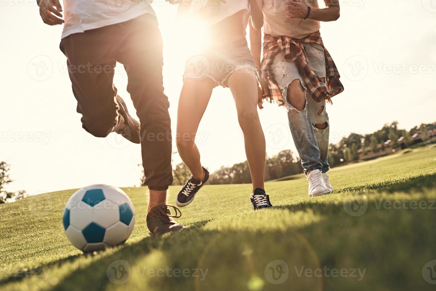 Nahaufnahme junger Menschen in Freizeitkleidung, die beim Fußballspielen im Freien laufen foto