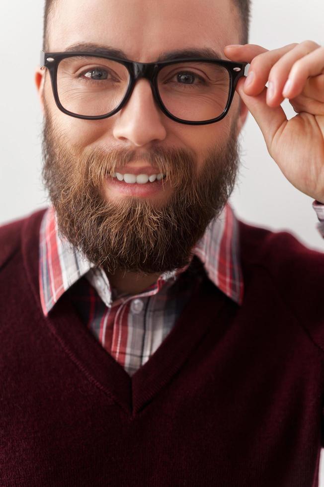 überzeugt von seinem hübschen Aussehen. Schließen Sie herauf Bild des gutaussehenden jungen Mannes im eleganten beiläufigen Anpassen seiner Sonnenbrille foto