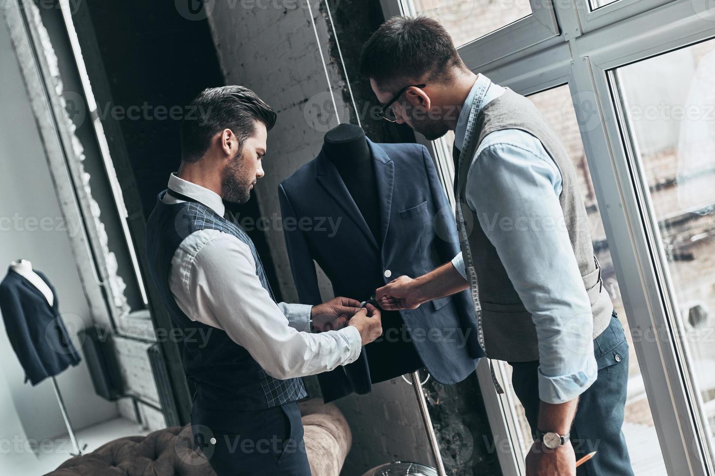 Wie gefällt Ihnen dieser junge modische Mann, der eine Jacke berührt, während er in der Werkstatt steht foto