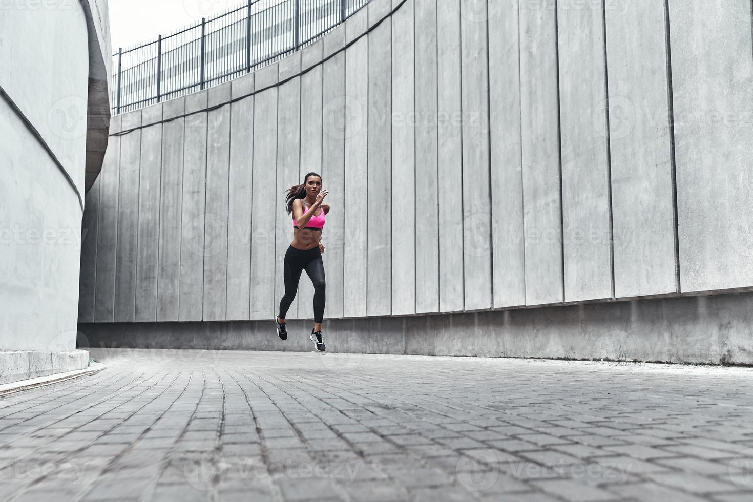 voller Energie. Volle Länge der jungen Frau in Sportkleidung beim Joggen im Freien foto