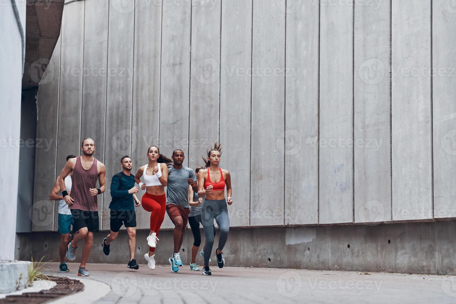 in voller länge von jungen leuten in sportkleidung, die beim training im freien joggen foto