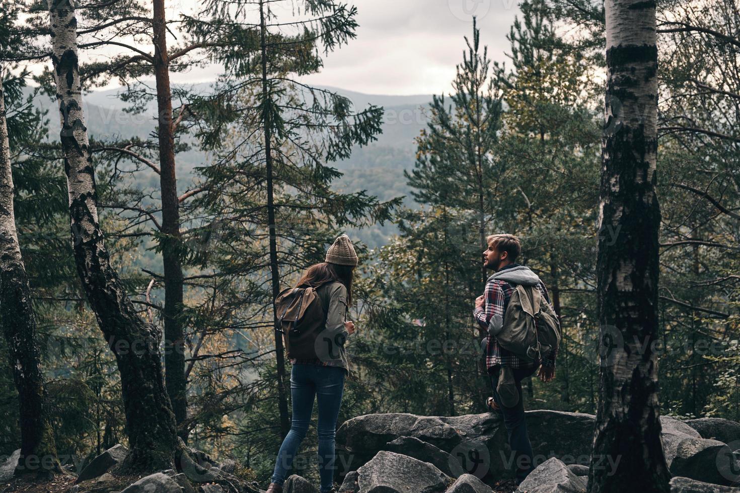 in der Mitte von Nirgendwo. junges Paar steht und schaut weg, während es gemeinsam im Wald wandert foto