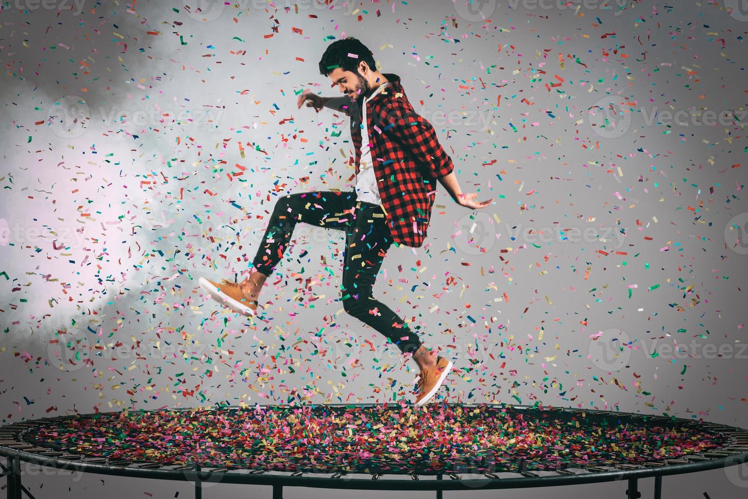 Trampolin Spaß. Luftaufnahme eines gutaussehenden jungen Mannes, der auf Trampolin springt, mit Konfetti um ihn herum foto