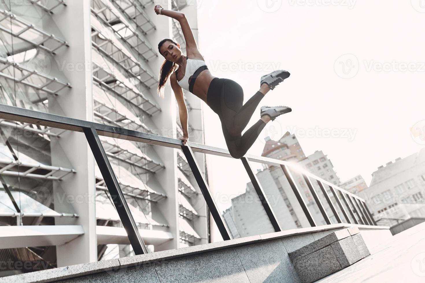 bis ans Limit treiben. in voller Länge von der modernen jungen Frau in der Sportkleidung, die beim Trainieren im Freien springt foto