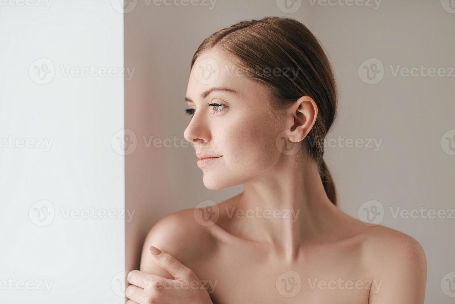 sich schön fühlen. attraktive junge Frau mit Sommersprossen im Gesicht, die wegschaut und die Hand auf der Schulter hält foto