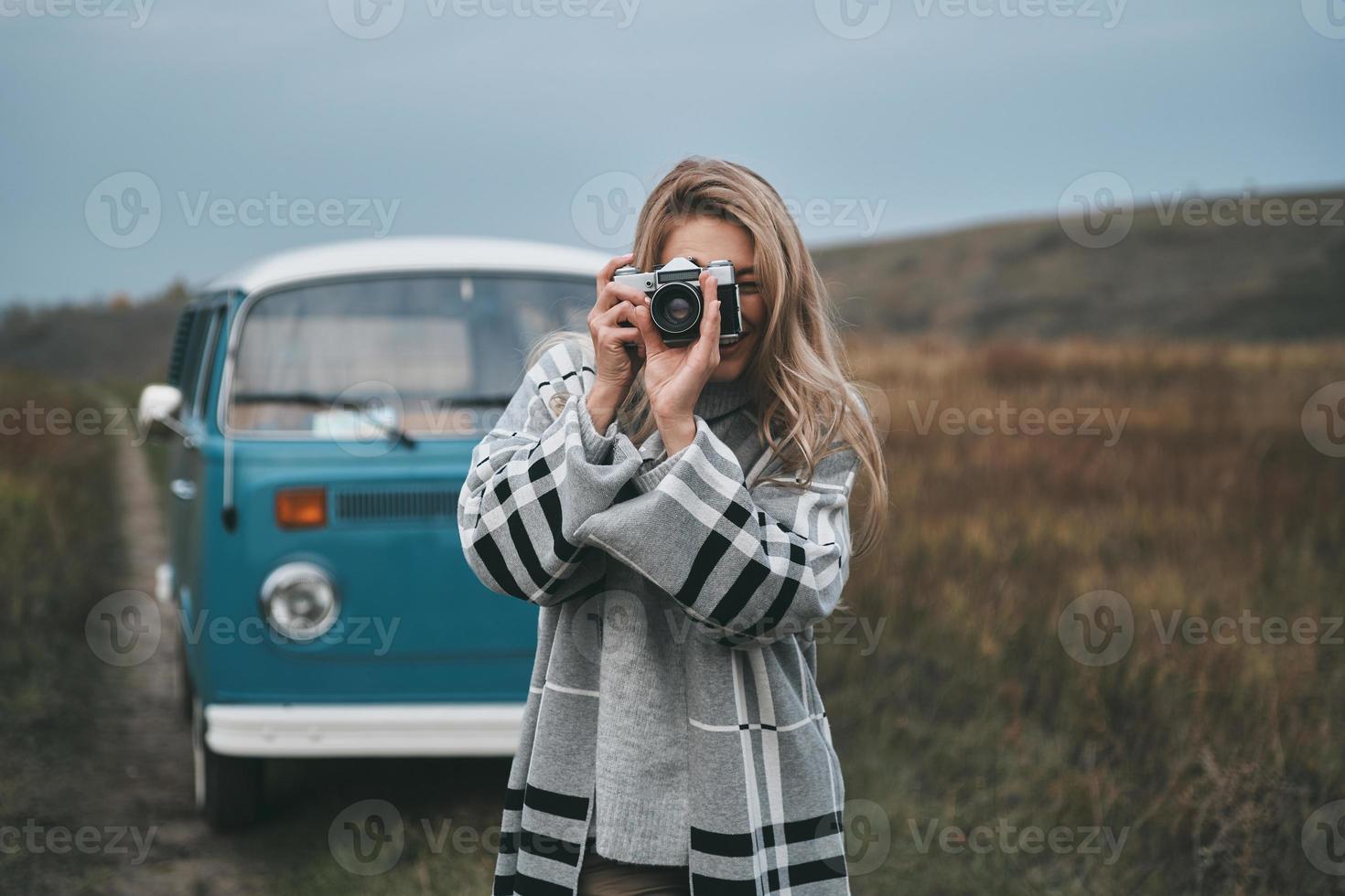 Moment festhalten. attraktive junge frau, die draußen fotografiert und lächelt, während sie steht foto