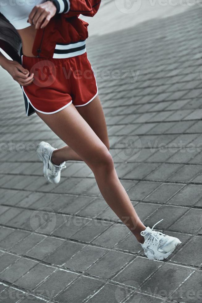 bemüht sich, ihr Ziel zu erreichen. Nahaufnahme einer jungen Frau in Sportkleidung, die im Freien läuft foto