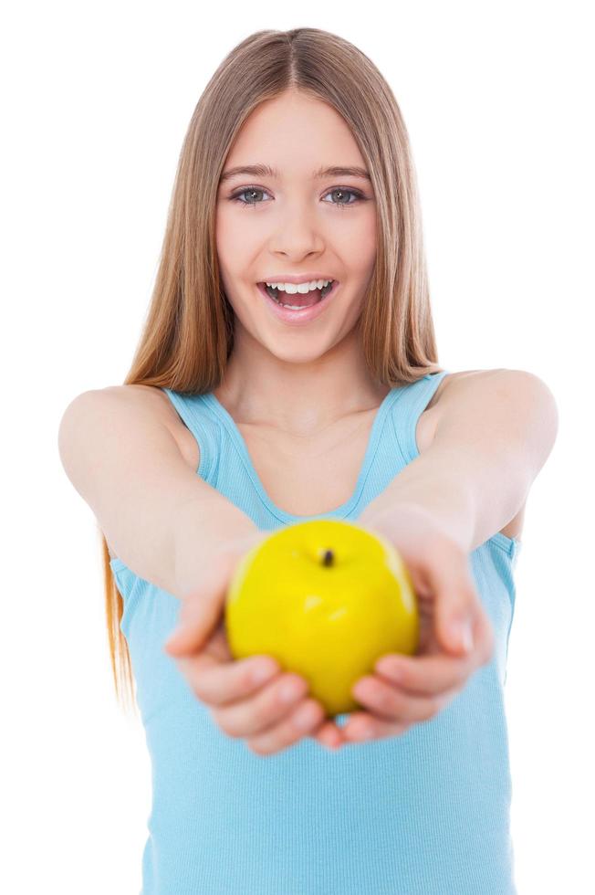 gesundes Essen mit Ihnen zu teilen. fröhliches Teenager-Mädchen, das sich grünen Apfel ausstreckt und lächelt, während es isoliert auf Weiß steht foto