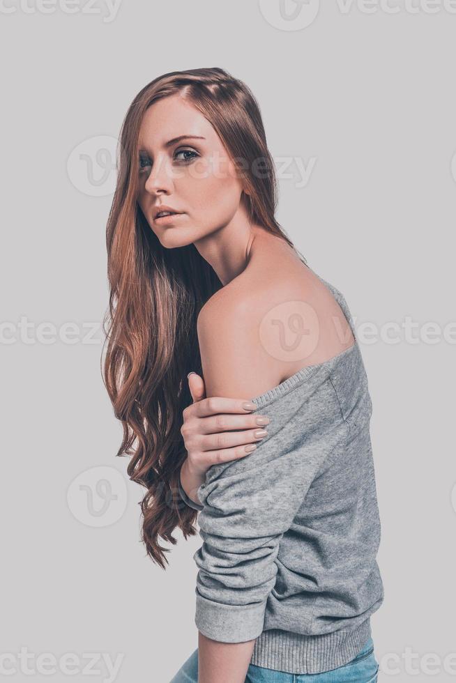 Porträt von Eleganz und Schönheit. Studioaufnahme einer attraktiven jungen Frau in Freizeitkleidung, die ihre Schulter zeigt und in die Kamera schaut foto