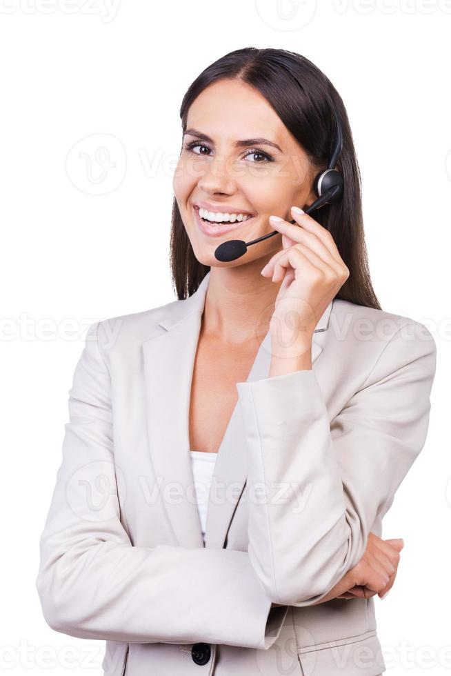 immer bereit, Ihnen zu helfen. schöne junge Geschäftsfrau, die ihr Headset anpasst und lächelt, während sie isoliert auf weißem Hintergrund steht foto