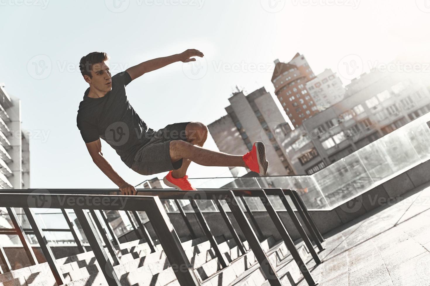 bestes Cardio aller Zeiten. voller Länge des jungen Mannes in Sportkleidung springen, während er draußen trainiert foto