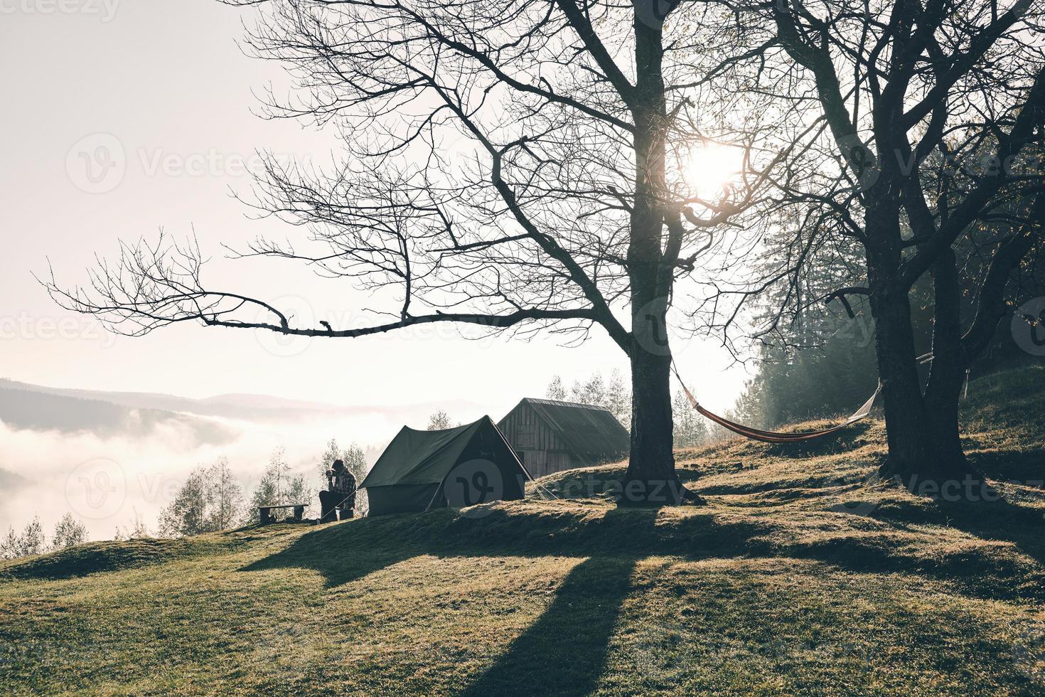 verliebt in die Natur. junger Mann, der beim Zelten in den Bergen in der Nähe des Zeltes sitzt foto