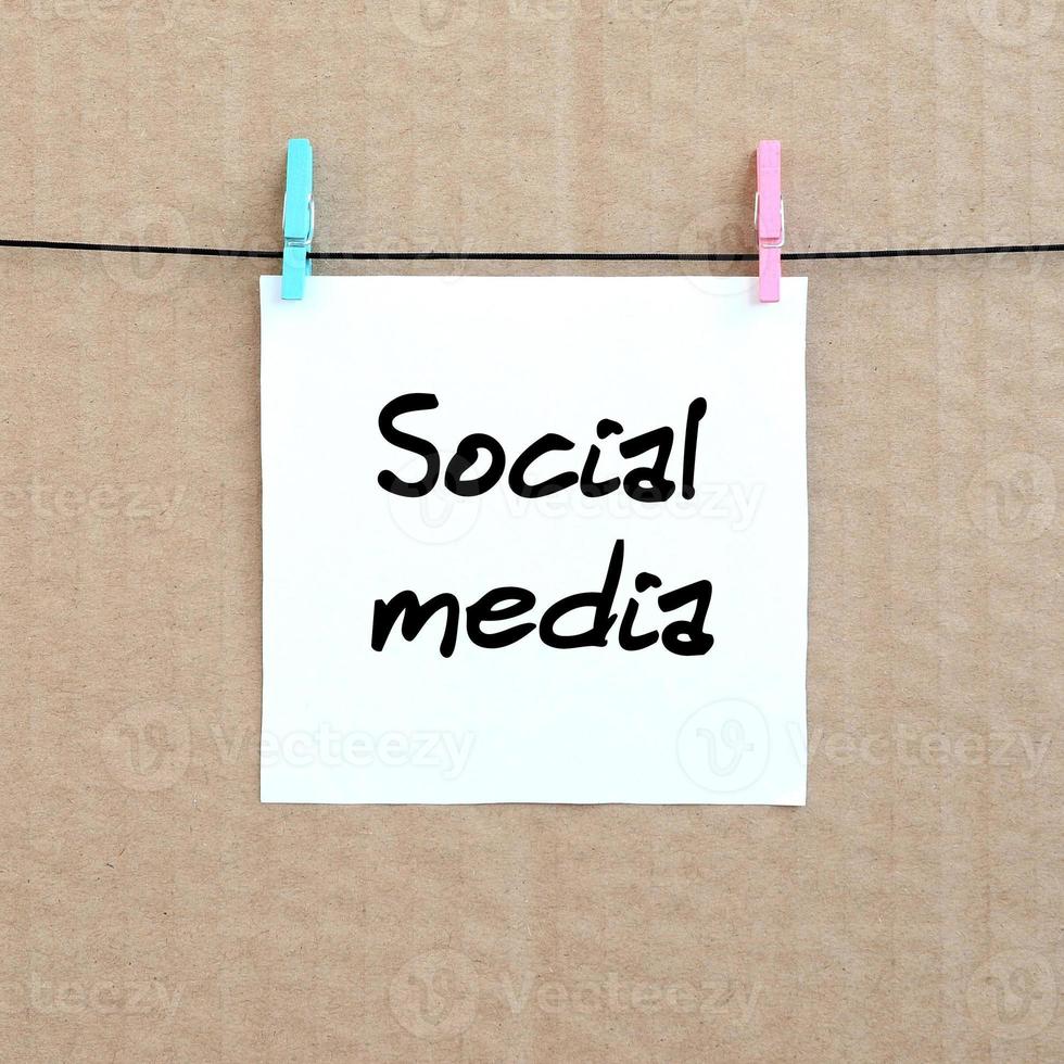 sozialen Medien. Notiz ist auf einem weißen Aufkleber geschrieben, der mit einer Wäscheklammer an einem Seil auf einem Hintergrund aus braunem Karton hängt foto
