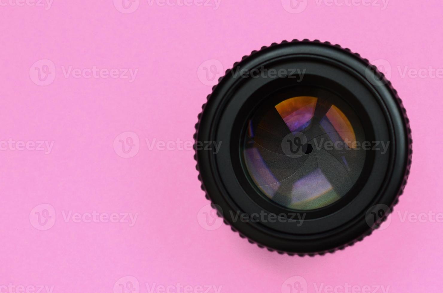 kameraobjektiv mit geschlossener blende liegen auf texturhintergrund von modepastellrosa farbpapier in minimalem konzept foto
