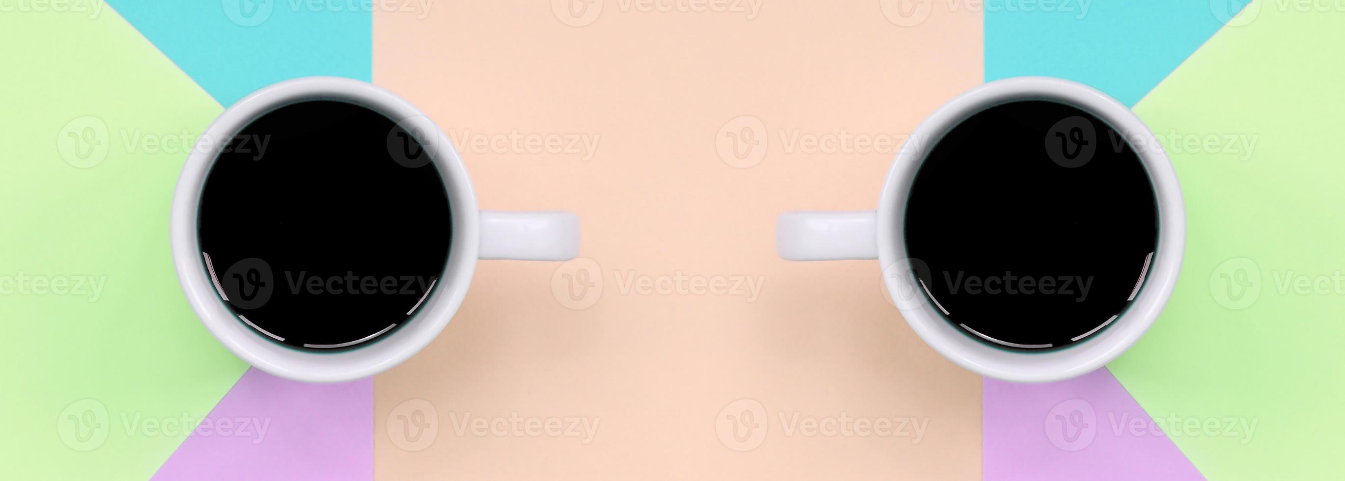 Zwei kleine weiße Kaffeetassen auf Texturhintergrund aus modischem Papier in Pastellrosa, Blau, Koralle und Limettenfarben foto