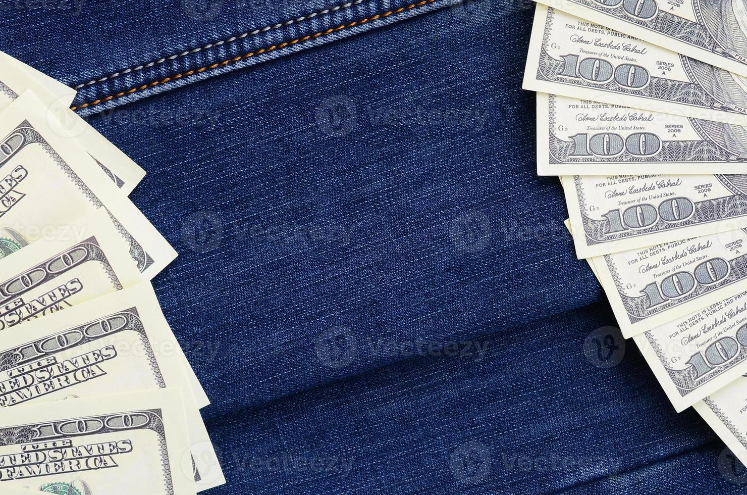 der fächer vieler us-dollar befindet sich auf einer dunklen jeansoberfläche. Hintergrundbild foto