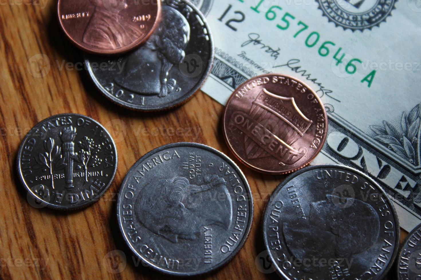 Dollarmünzen und Dollarscheine, die auf einem Holztisch verstreut sind, Dollarmünzen flach liegen. foto