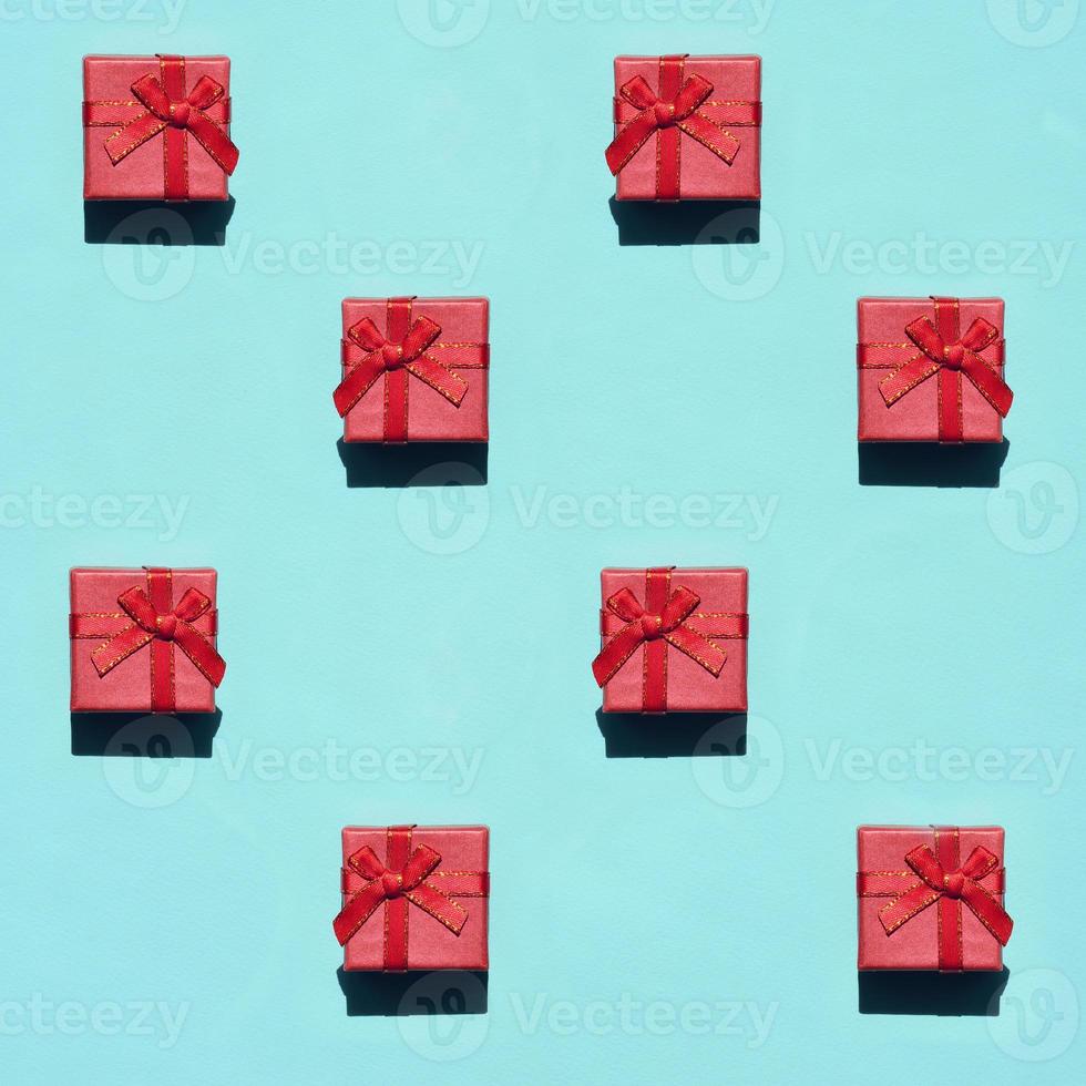 viele kleine rot-rosa geschenkboxen auf texturhintergrund von modischem pastellblauem papier in minimalem konzept. abstraktes Muster foto
