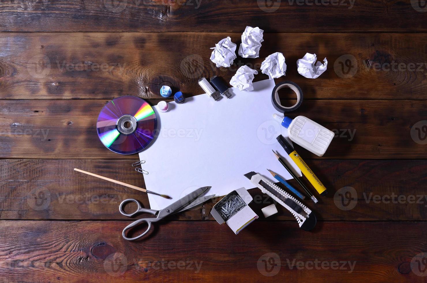 ein Schul- oder Bürostilleben mit einem weißen leeren Blatt Papier und vielen Büromaterialien. Die Schulmaterialien liegen auf einem braunen Holzhintergrund. Platz für Texte foto