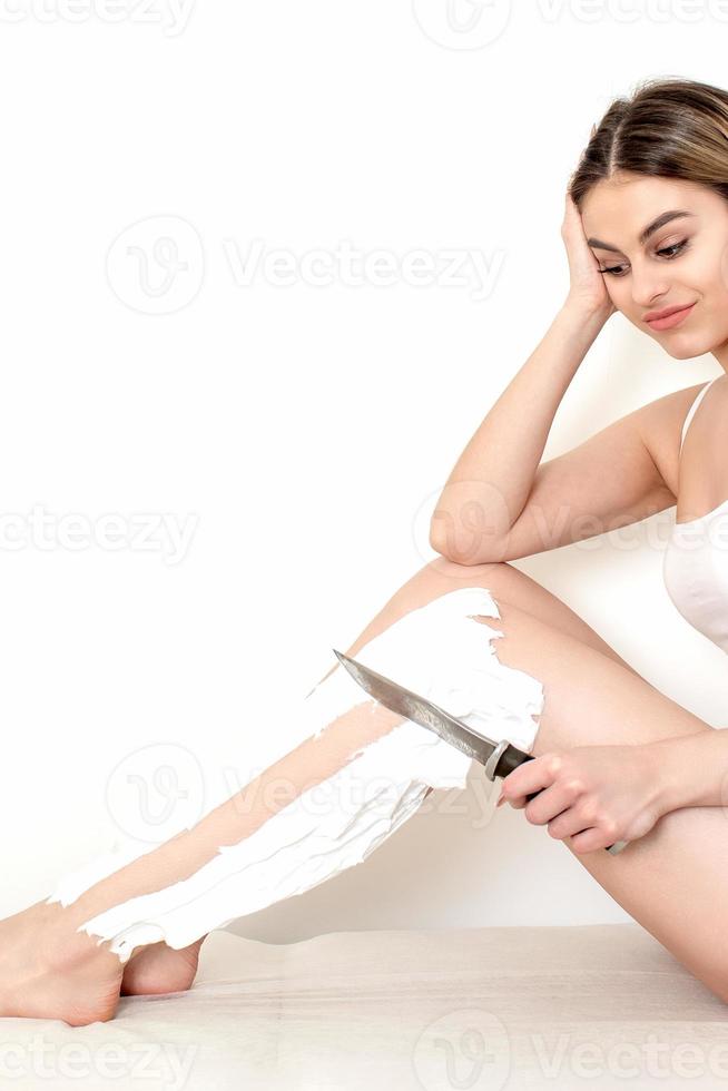 Frau rasiert ihre Beine mit einem Messer foto
