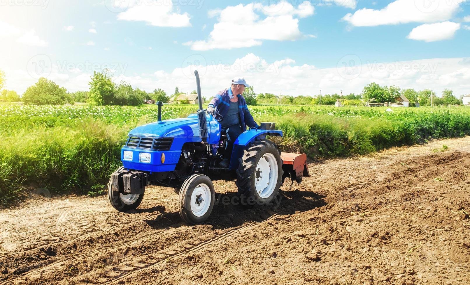 Ein Bauer fährt auf einem Traktor mit Fräse über das Feld. Lockerung der Oberfläche, Anbau von Flächen für die Bepflanzung. Landwirtschaft und Ackerbau. Arbeit auf dem Bauernhof. Bodenvorbereitung für die Anpflanzung von Feldfrüchten. foto