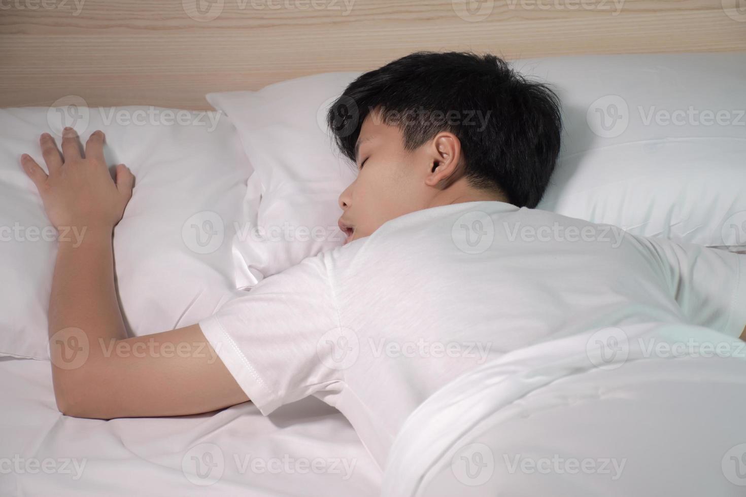asiaten schlafen auf einem weißen bett in seinem zimmer. Asiaten sind müde von der Arbeit. foto