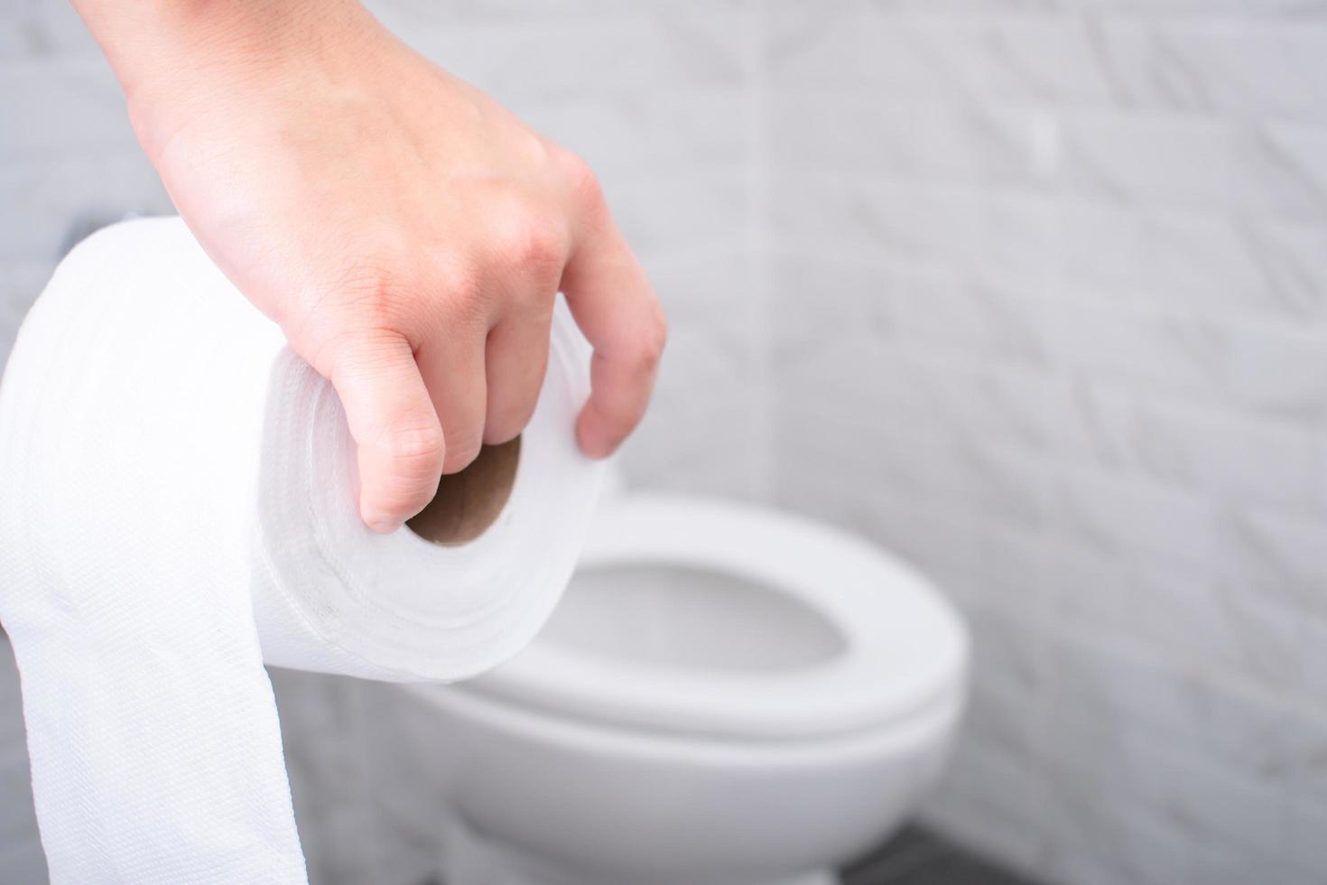 Nahaufnahme der Hand, die ein Toilettenpapier in der Toilette hält. foto